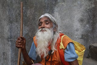 An elderly spiritual teacher sits and watches.