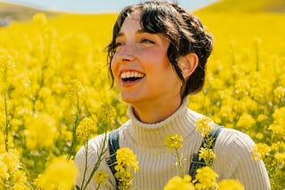 Woman smiling in yellow flowers with words “spring spirit energy refresh” in front of her.