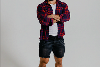 Youtuber Alex Homorzi in an unbuttoned red plaid shirt, white t-shirt underneath, black denim shorts, white socks and crocs