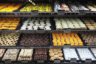 Shelves of cupcakes, cookies, and brownies on display for sale at a bakery.