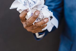 A hand holding a crumpled bunch of papers.