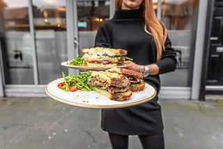 A woman holds plates of tempting sandwiches