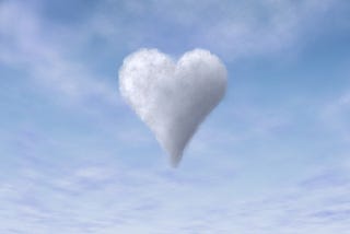 A white heart shaped cloud in a baby blue sky