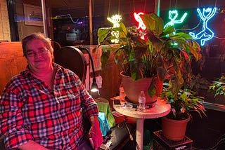friendly lesbian bar staff sits at the entrance of Babe’s of Carytown in virginia with a pot plant next to her