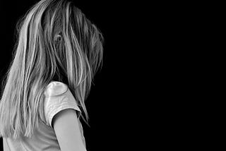 A black and white image of a tween, long-haired, sad-looking girl.