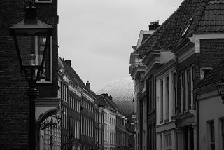 Black and white photo of a street at the end of which a shiny dome can be seen.