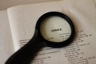 A photo of a magnifying glass over the index page of a book.