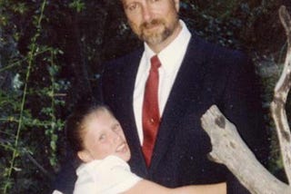 Picture of Dr. Robert Reid with his daughter hugging him.