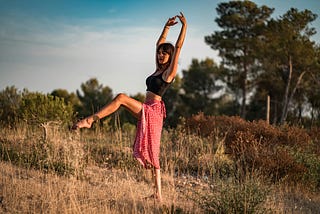 Calm dancer standing in field. Can you hack your menstrual cycle to boost your health & fitness goals?