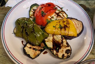 a plate of colorful vegetables showing red, yellow and green peppers on top