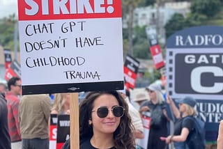 Striking Hollywood screenwriter holding up sign saying “ChatGPT Doesn’t Have Childhood Trauma.”