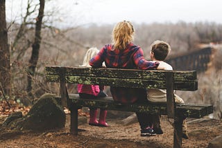 woman sitting on a bench with 2 children