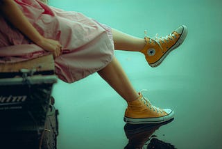 Woman wearing a pink dress and yellow Converse All Star High Top Sneakers.