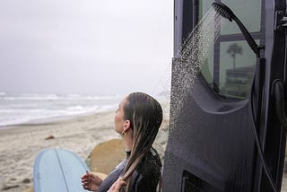 Woman showering in campervan post-surf