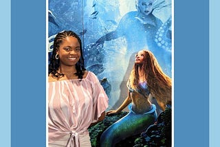 A Black woman posing with The Little Mermaid (2023) movie poster.