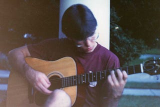 Old photo of a teenage boy playing guitar