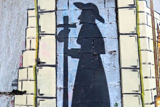 Wall art shows a silhouette of St. James, wearing a long robe and a wide-brimmed hat. He holds a staff with a cross at the top and a small bag that is attached