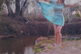 photo of a woman in a blue dress, twirling in the sand