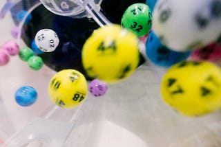 Lottery balls in air image for article by Lori Quayle on why we need better lottery games.