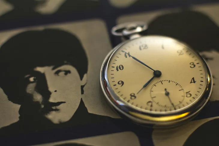 A pocket watch sits atop an image of Beatle Paul McCartney