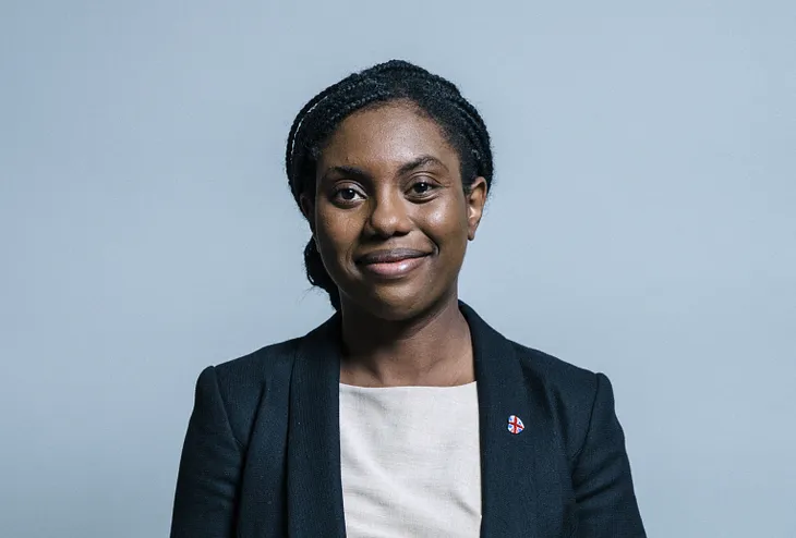 Photographice potrait of Kemi Bademoch, Minister for Women and Equalities. Kemi is a smartly dressed woman of colour, posing for an offical portrait.