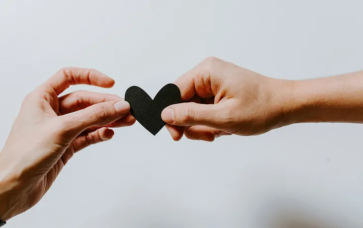 A person’s hand offering a heart to another person’s hand