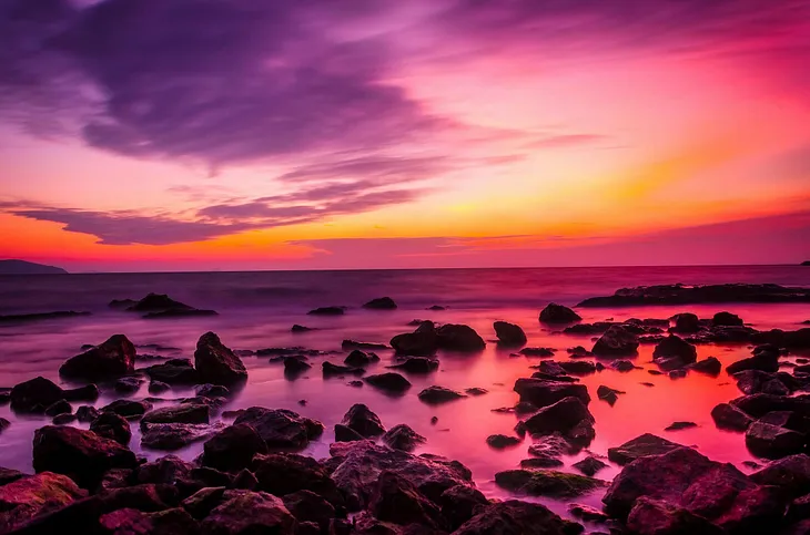 A rocky beach bathed in purple hues