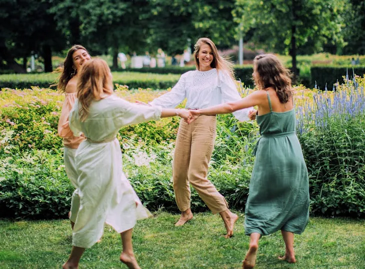 Four women in a circle dancing outside.