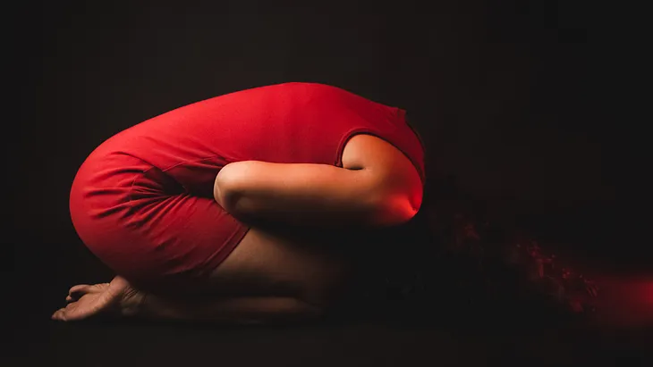 Woman in a red dress doubles over in pain