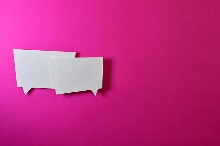 Two square white speech bubbles on a bright pink background.