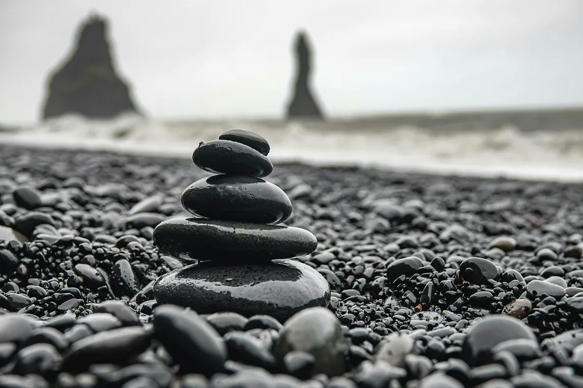 A black and white image of wet stacked stones on a beach